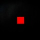 Vivid red square centered on a minimalist black background, creating a striking visual contrast.