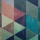 A vibrant geometric abstract design featuring multicolored triangles with a textured, artistic finish.